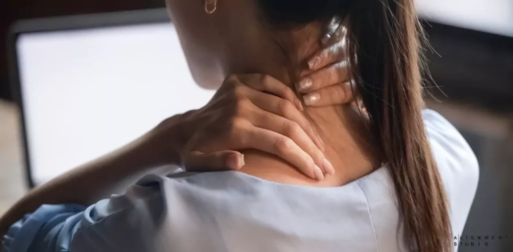 Young woman holding her neck in pain, showing signs of neck soreness or stiffness.