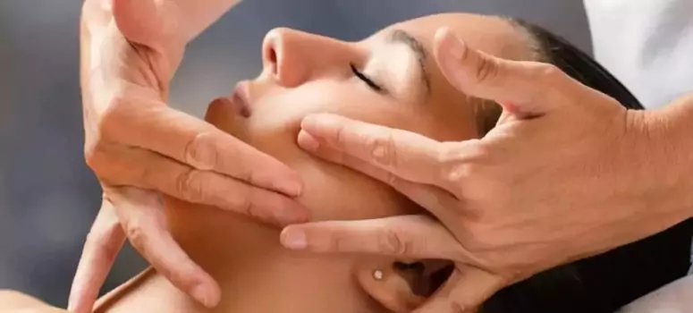 Physiotherapist performing manual therapy on a woman’s jaw to relieve TMJ pain and improve movement during a physiotherapy session in Melbourne.