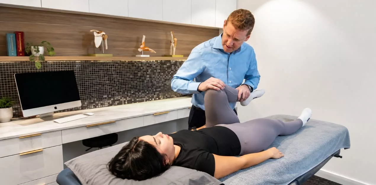 Practitioner assessing a patient's leg during treatment at a Melbourne allied health clinic